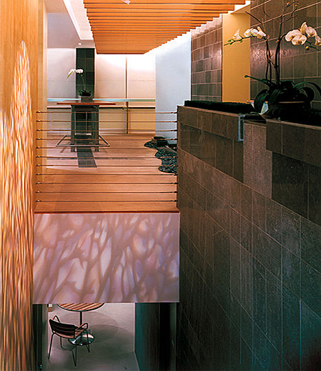 In the atrium, a row of suspended beams house fluorescent up-lights.  Their light, reflecting off the concrete slab above, creates the impression of an exterior pergola structure.  