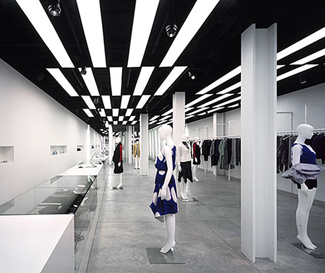 The implied lighting technique helps resolve the spaceâ€™s physical constraints. The buildingâ€™s ceiling, pipes, ducts, and power supply system are painted black. A black metal strut frame system hangs from the ceiling at a height of 10 feet above the floor. It supports the custom-made back-lit panels, as well as the lighting tracks.