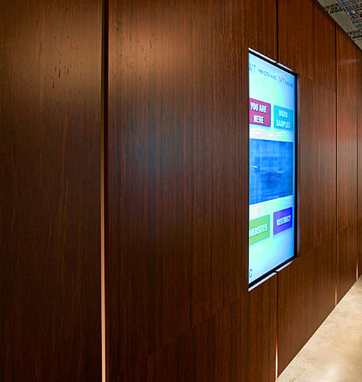 The buildingâ€™s service core is wrapped in floating panels of bamboo plywood, which accommodates all sorts of narrative mediums: video monitors, projection screens, LED displays and whiteboards. The circulation area around the service core is lit with a row of seamless fluorescent lights concealed at the bottom edges of the floating panels.