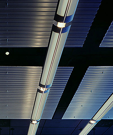 A French company, Synelec produces super-scale monitors that are used in military and civil aviation, police work, and traffic control. Because of budgetary constraints, the design of Synelecâ€™s first US showroom relies on lighting to define the environment.  Suspended metal panels are complemented by up-lights with perforated metal reflectors.  The fluorescent lights concealed below the trapeze-shaped tabletop contribute to the illusion that all elements of the interior are detached from the showroomâ€™s surrounding structure.